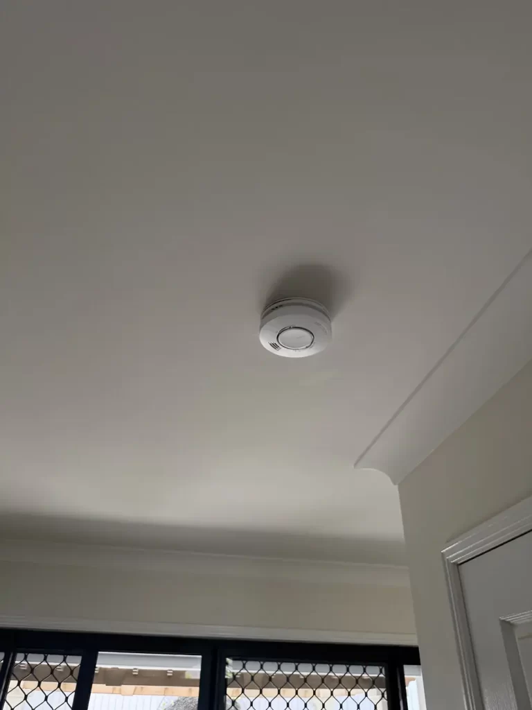 Hardwired smoke alarm with RF interconnection fitted in a bedroom in Carindale, Brisbane